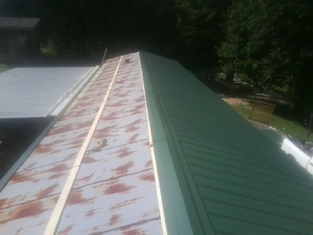 Old rusted panels beside newly installed green metal roofing — Wind Damage Roof Repair by Roofing Brothers in Greenwood Springs