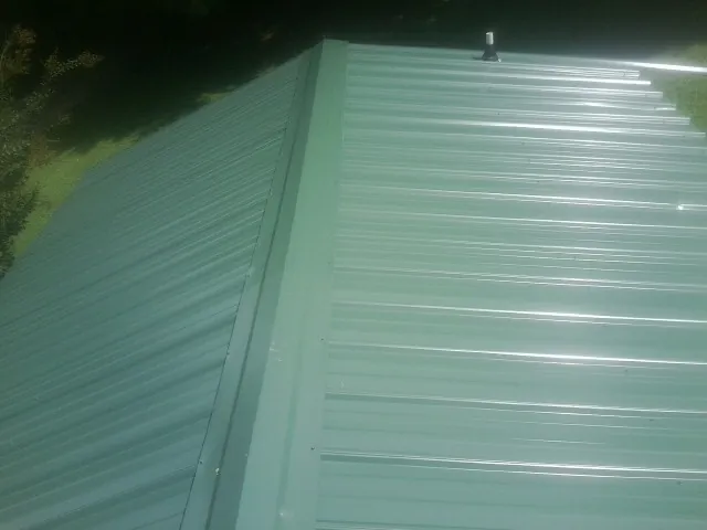 New green metal panels meeting at the ridge of a roof — Flat Roof Repair work by our crew in Greenwood Springs