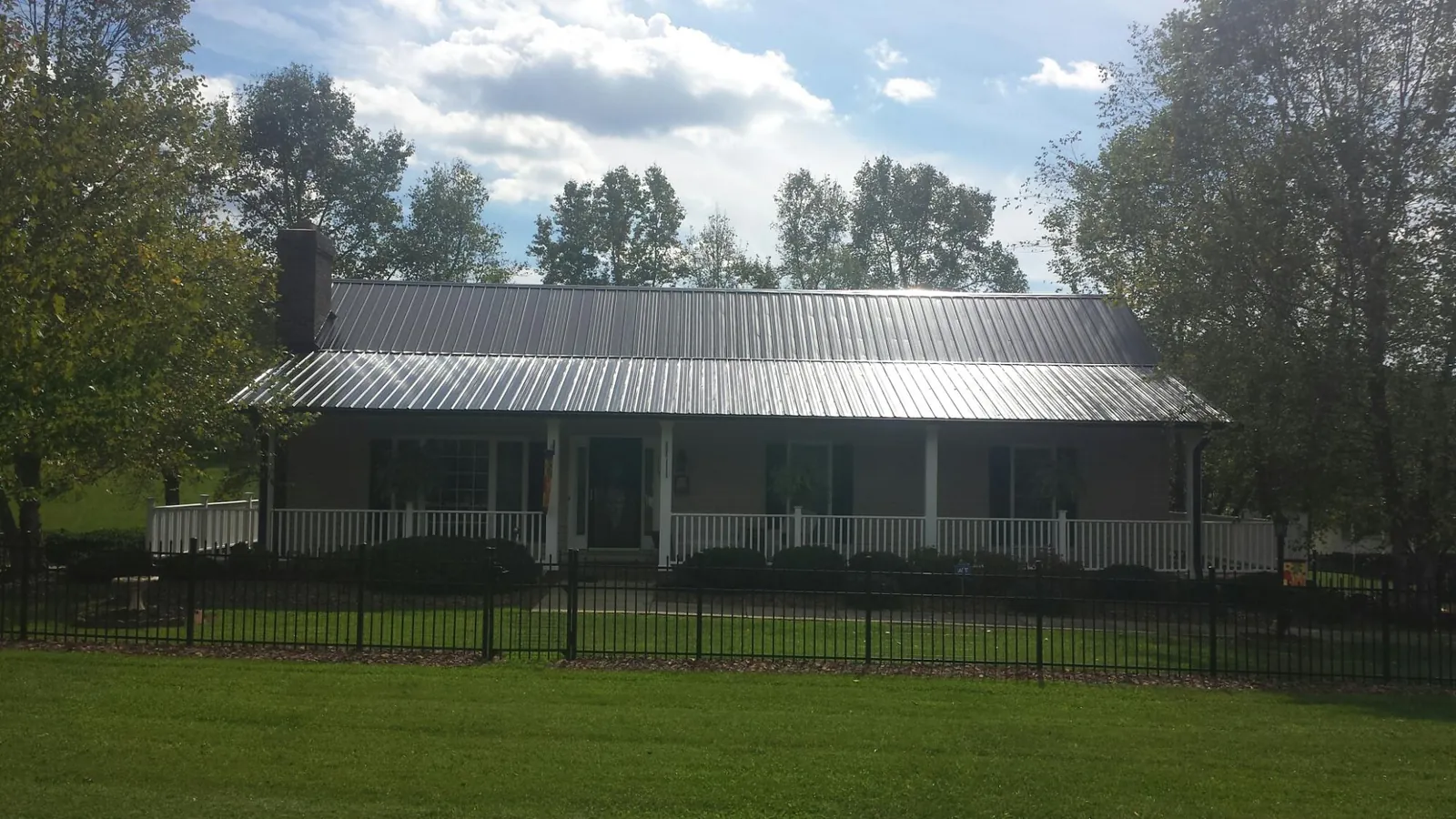 Gray metal roof on a brick ranch with a full width front porch — Gutter Guard Installation work by our crew in Greenwood Springs