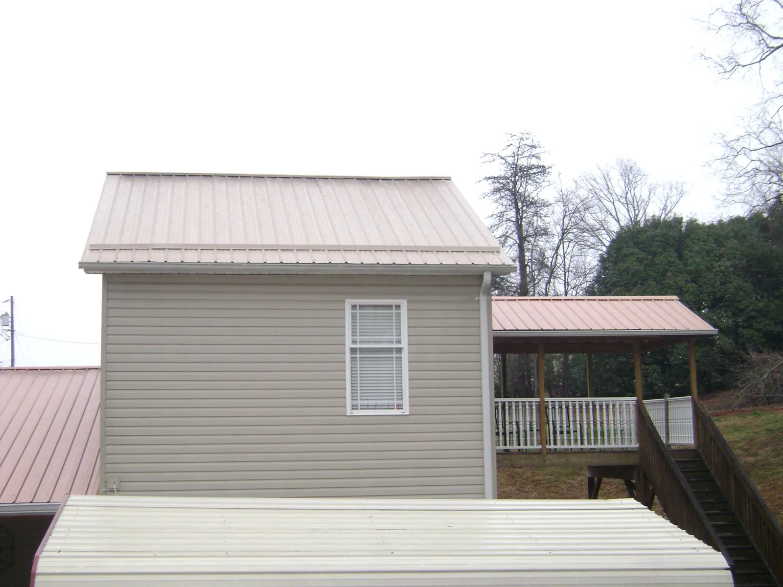 Tan metal roofs on a two story addition and attached porch, from a Roof Replacement job in Greenwood Springs