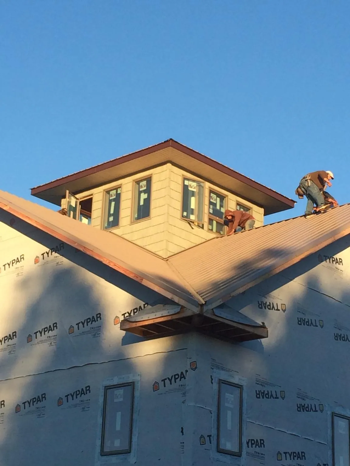 Roofers working around a rooftop cupola on a new metal roof at sunset — Roof Waterproofing in Greenwood Springs by Roofing Brothers
